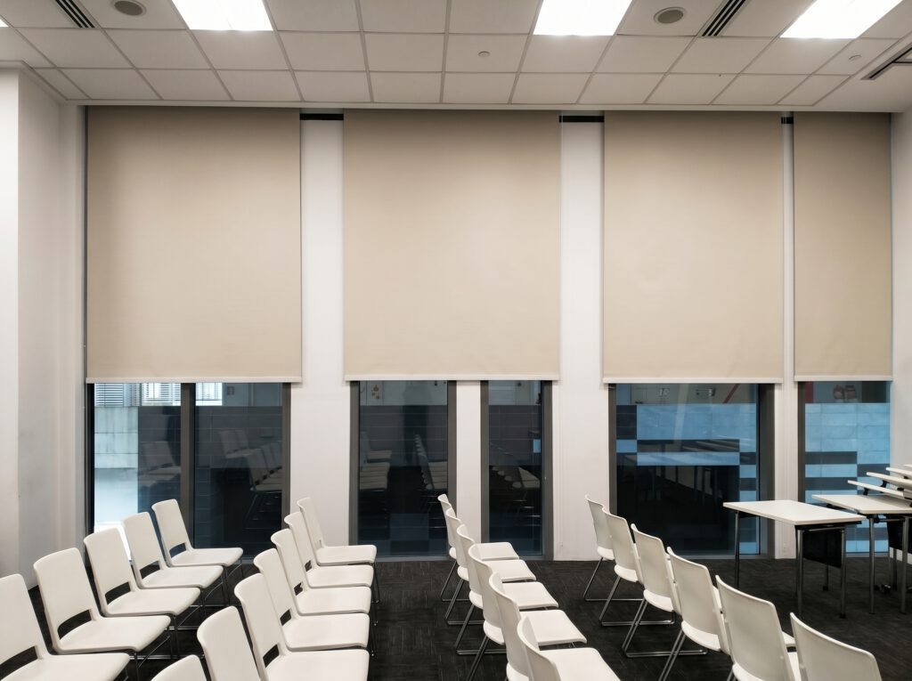 Blackout roller blind on floor-to-ceiling office window in Raffles Place Singapore CBD, full light blockage for focused work and AV use in commercial workspace