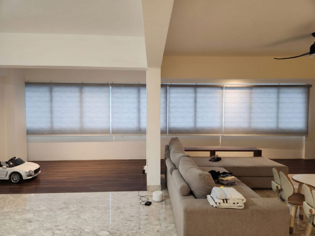 Dimout roller blind in a spacious 5-room HDB flat living room in Jurong Singapore, warm diffused daylight through cream fabric, modern heartland home interior
