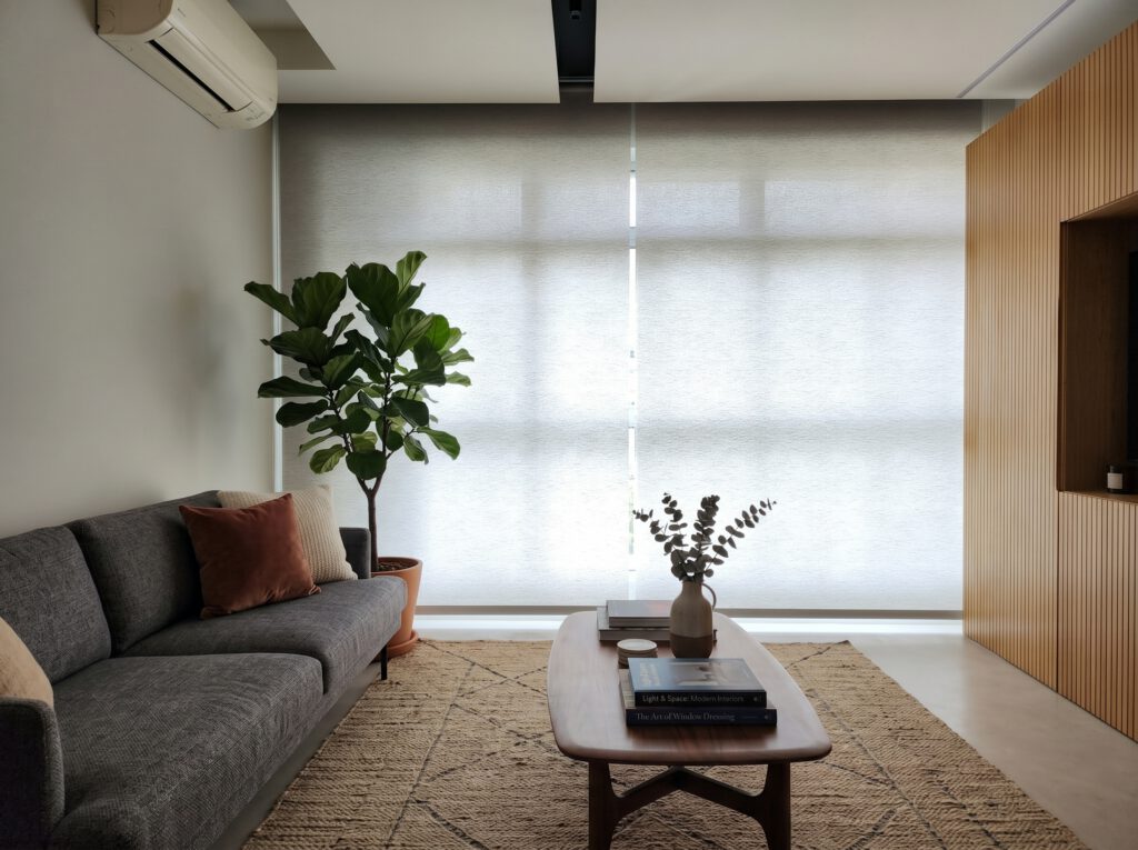 Dimout roller blind in a bedroom of an Ang Mo Kio HDB Singapore, gentle morning glow filtering through cream roller blind fabric, restful and cosy waking atmosphere