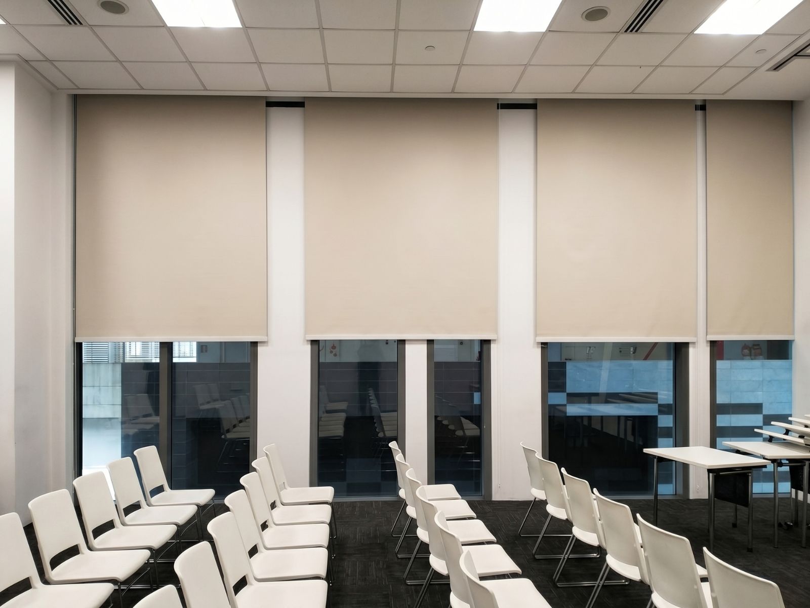 Blackout roller blind on floor-to-ceiling office window in Raffles Place Singapore CBD, full light blockage for focused work and AV use in commercial workspace