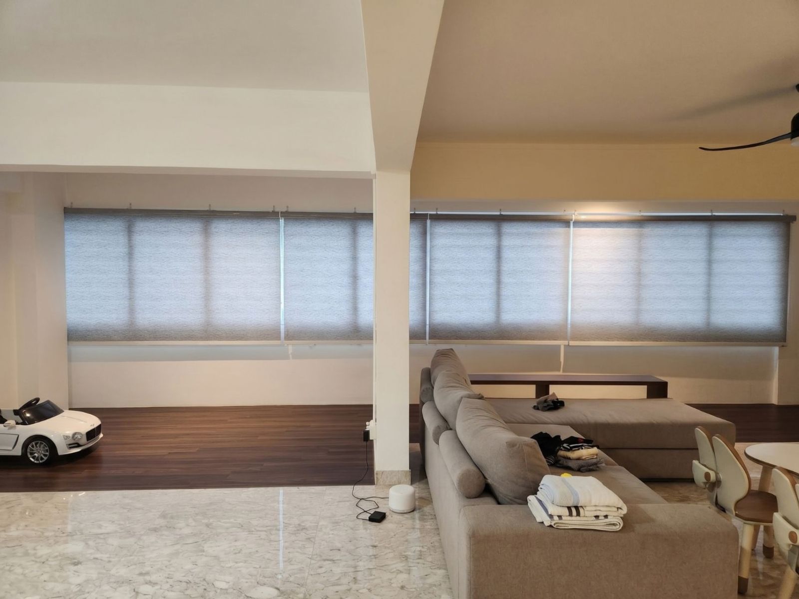 Dimout roller blind in a spacious 5-room HDB flat living room in Jurong Singapore, warm diffused daylight through cream fabric, modern heartland home interior