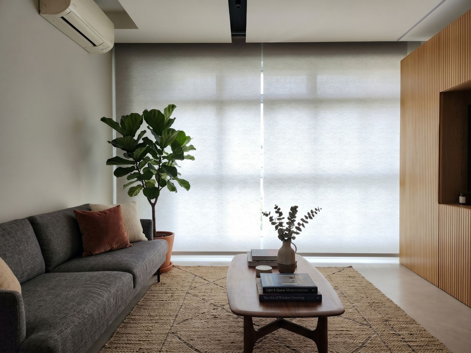 Dimout roller blind in a bedroom of an Ang Mo Kio HDB Singapore, gentle morning glow filtering through cream roller blind fabric, restful and cosy waking atmosphere