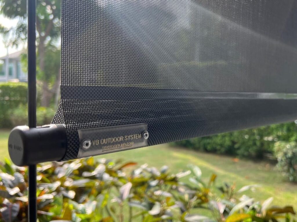 VB Blind outdoor roller blinds in Singapore featuring a black round bottom bar, mesh fabric and branded VB Outdoor System metal plate.